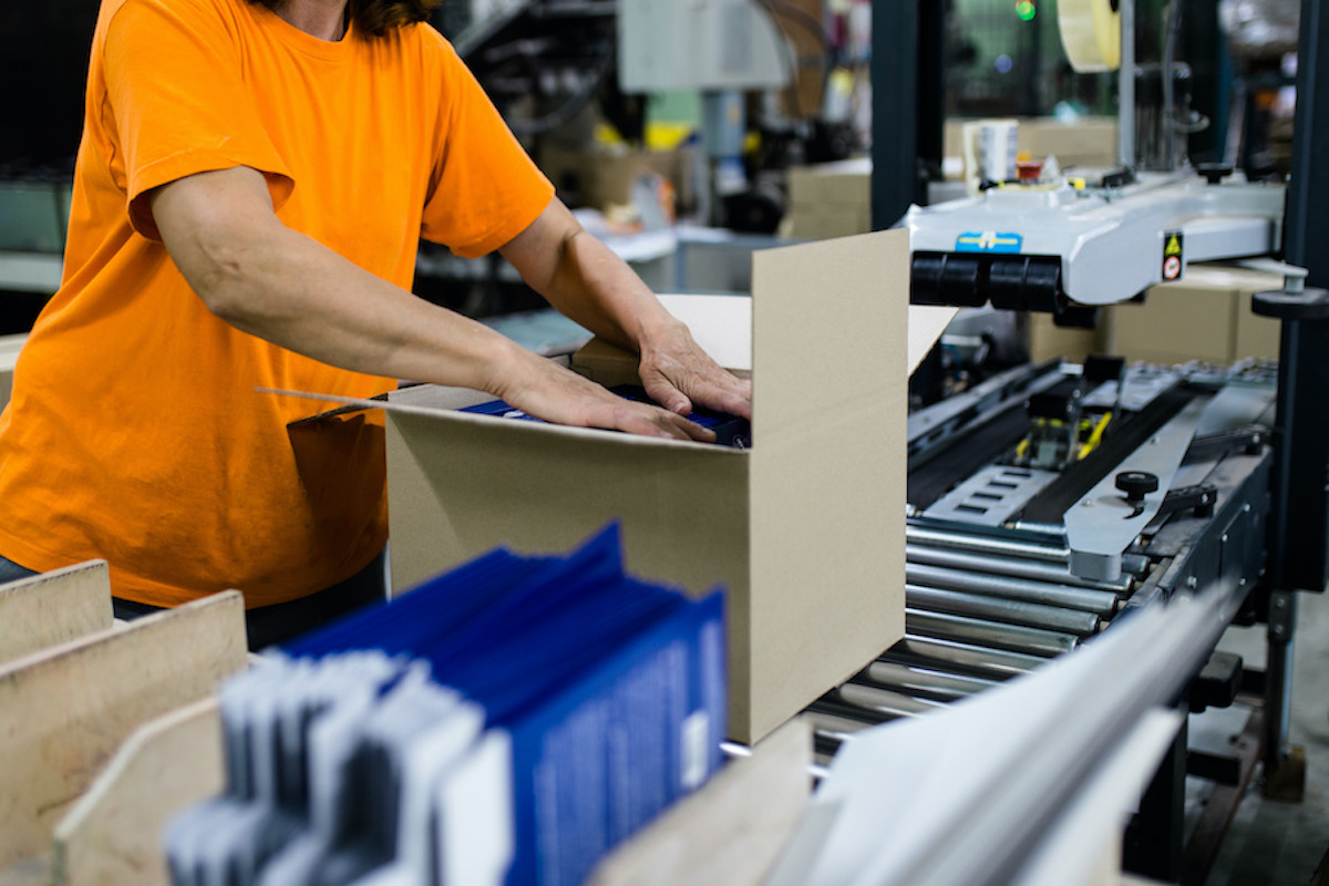 Close up shot of worker's hand preparing carton for printing in a modern printing house.
